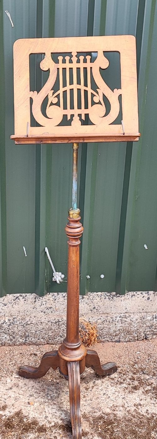 A Victorian walnut music stand featuring a fretwork lyre rest, height-adjustable brass stem, turned column, and carved tripod legs. View VII