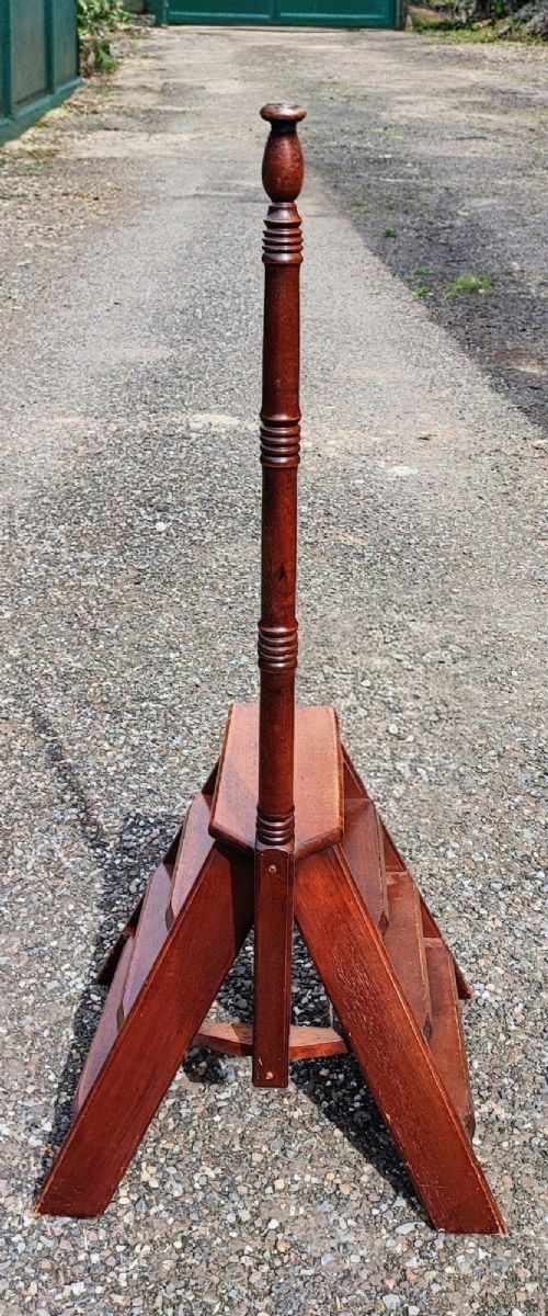 A set of wooden mahogany library steps featuring three treads, an A-frame support structure, and a tall turned wooden pole topped with a finial. View II