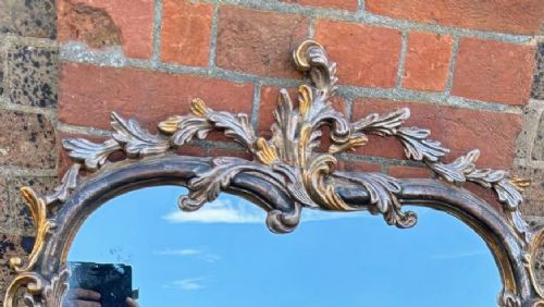 A large 20th-century Italian wall mirror featuring an arched top and an ornate carved wood frame finished in silver and gold leaf with acanthus leaf motifs. View II