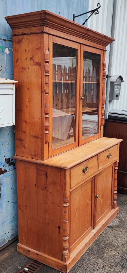A two-piece stripped pine dresser featuring a glazed upper display cabinet with two doors and a lower section with two drawers above twin cupboard doors. View III