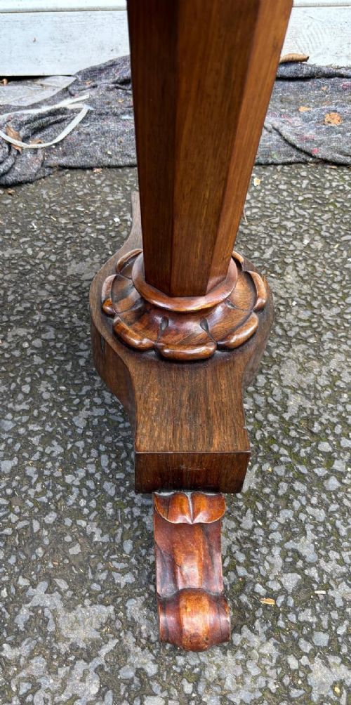 A rectangular antique rosewood window table featuring a highly figure-grained top, a scalloped frieze with drop pendants, and twin carved pedestal supports on lotus trestle feet. View IV