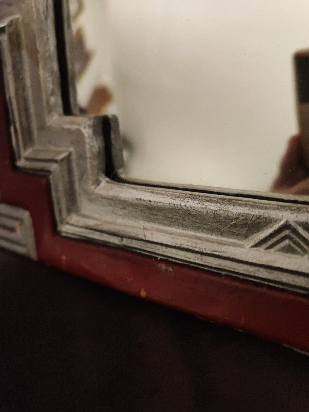 An English Art Deco wall mirror featuring a stepped geometric frame painted in terracotta red and off-white. View III