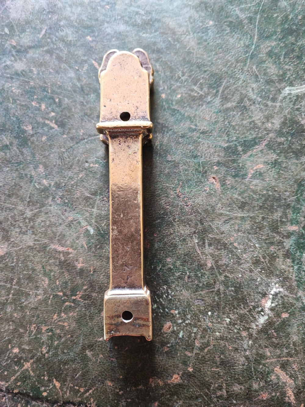 A small cast brass novelty door knocker shaped like a miniature grandfather clock with a detailed dial and pedestal base. View IX