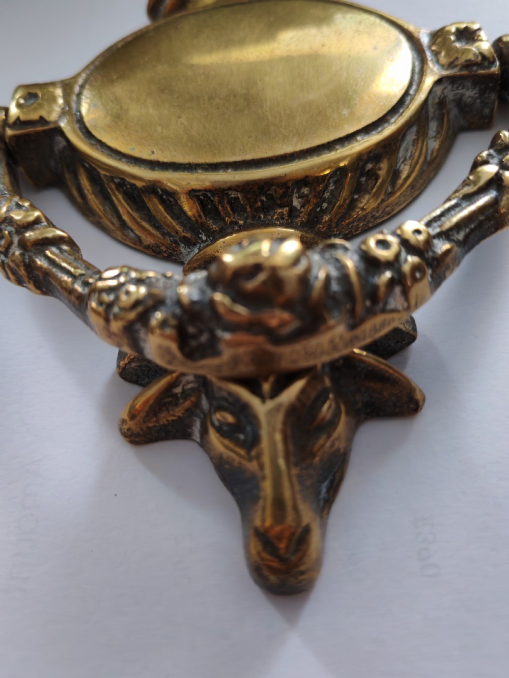 A cast brass Neoclassical style door knocker shaped like an urn with a floral patterned hinged ring. View II