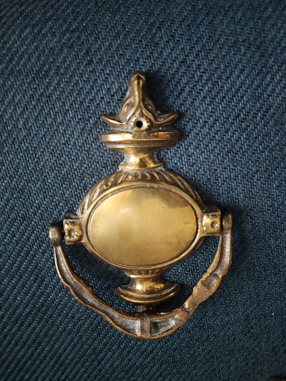 A cast brass Neoclassical style door knocker shaped like an urn with a floral patterned hinged ring. View III
