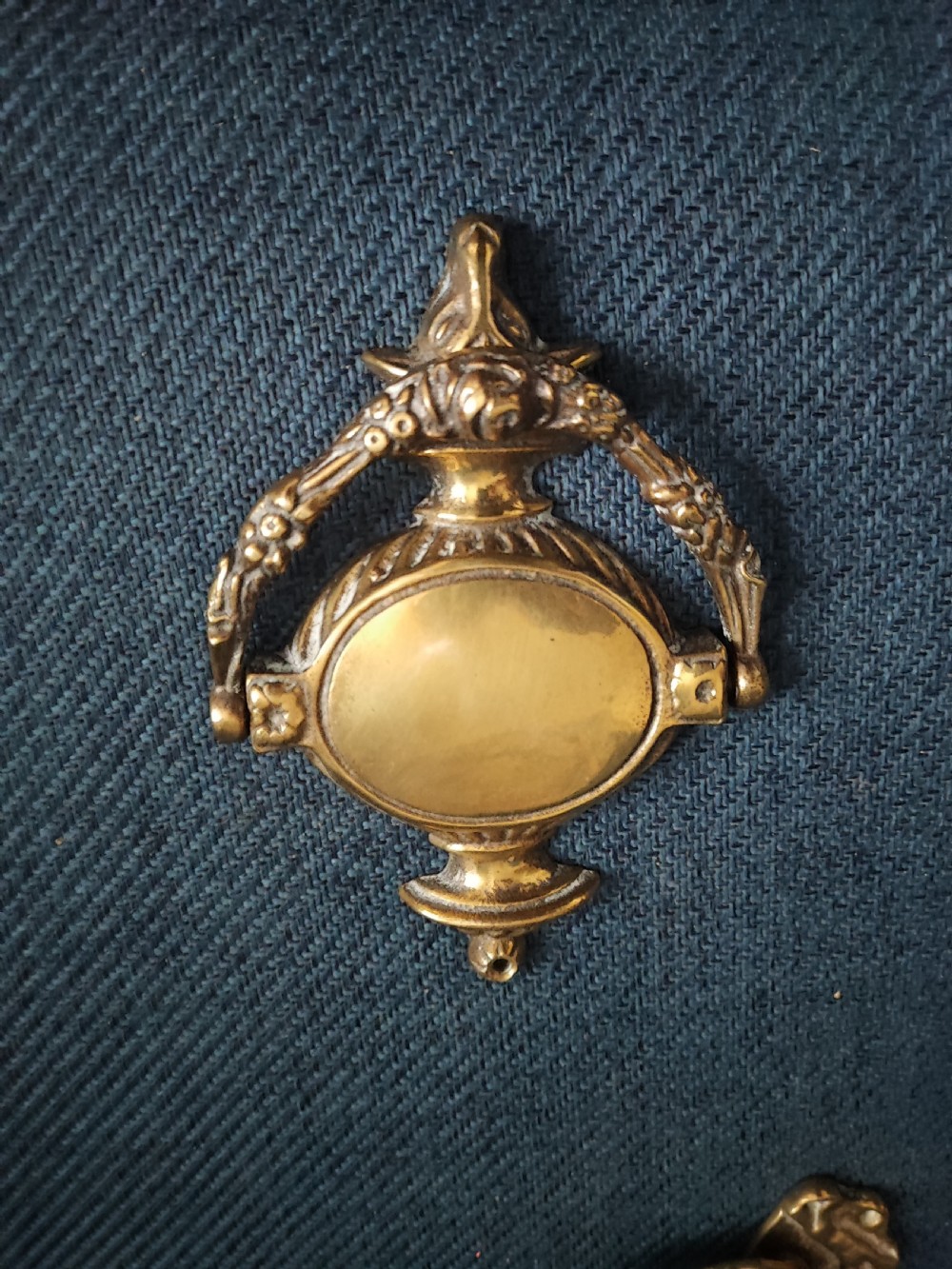 A cast brass Neoclassical style door knocker shaped like an urn with a floral patterned hinged ring. View VI