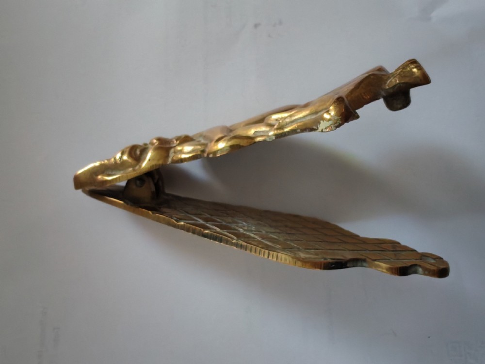 A cast brass door knocker depicting a seated imp perched upon a toadstool with pointed ears and knees drawn up. View III