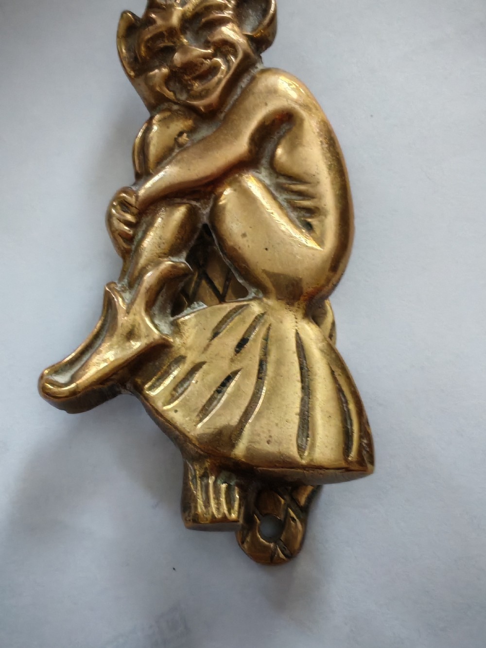 A cast brass door knocker depicting a seated imp perched upon a toadstool with pointed ears and knees drawn up. View VII