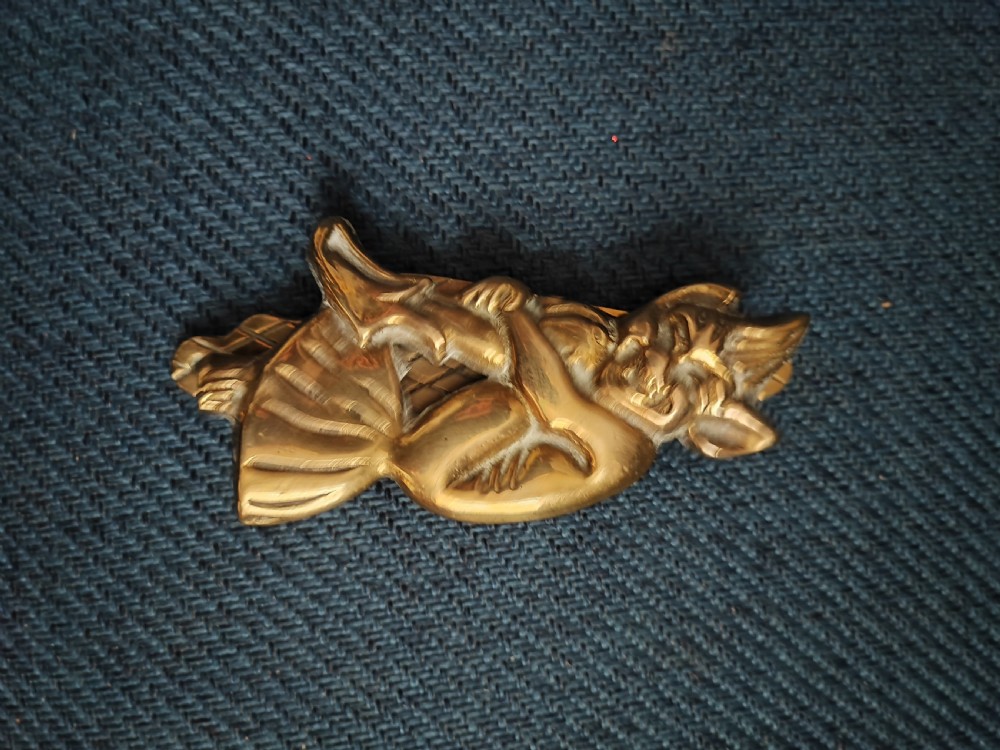 A cast brass door knocker depicting a seated imp perched upon a toadstool with pointed ears and knees drawn up. View XII