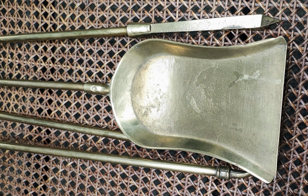 A set of three Victorian brass fire irons, including tongs, a shovel, and a poker with turned finial handles resting on a woven surface. View III