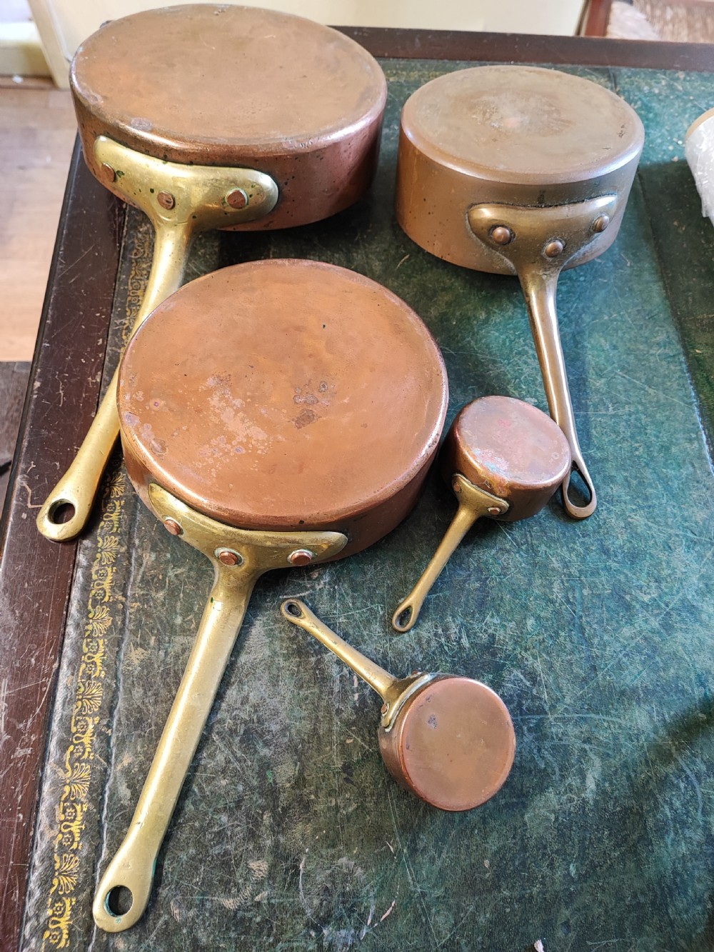 A set of five Victorian graduated copper saucepans featuring cast brass handles secured with heavy copper rivets. View VIII