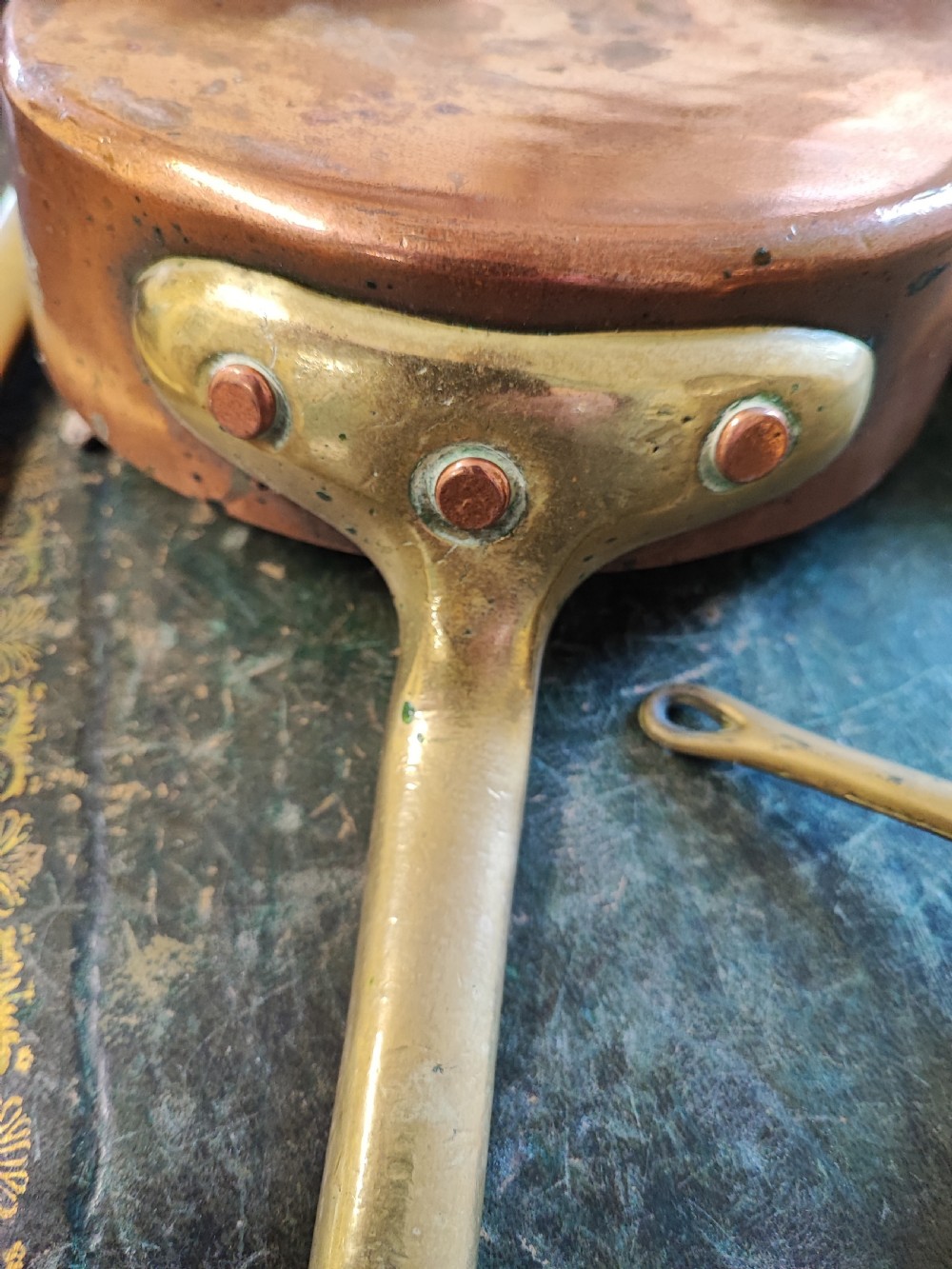 A set of five Victorian graduated copper saucepans featuring cast brass handles secured with heavy copper rivets. View X