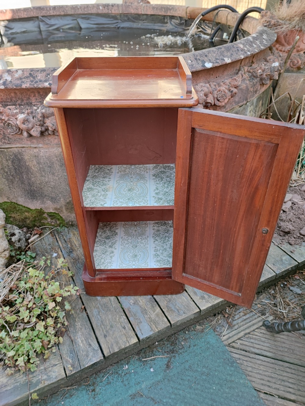 A tall Victorian mahogany bedside cabinet featuring a gallery top, a single recessed panel door with a wooden turned knob, and a solid plinth base. View IV