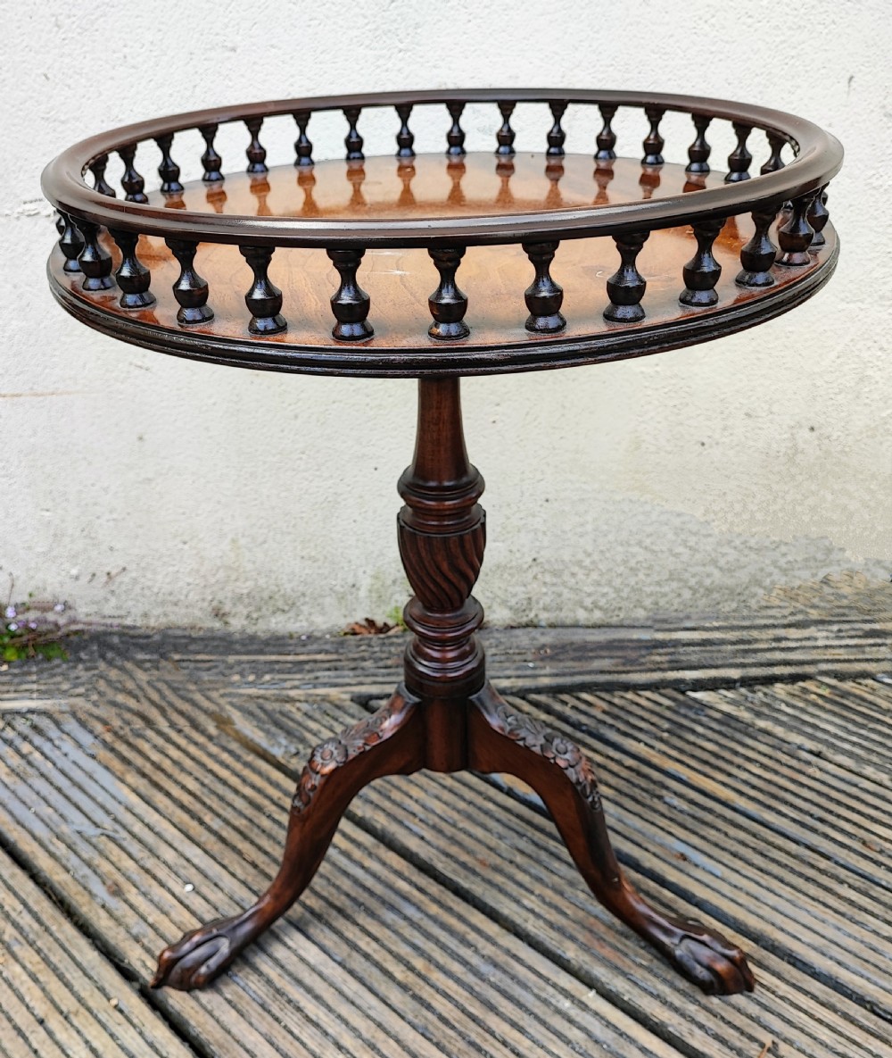 An antique George III style mahogany wine table featuring a spindle gallery rim, a turned spiral twist stem, and carved tripod cabriole legs with claw and ball feet.