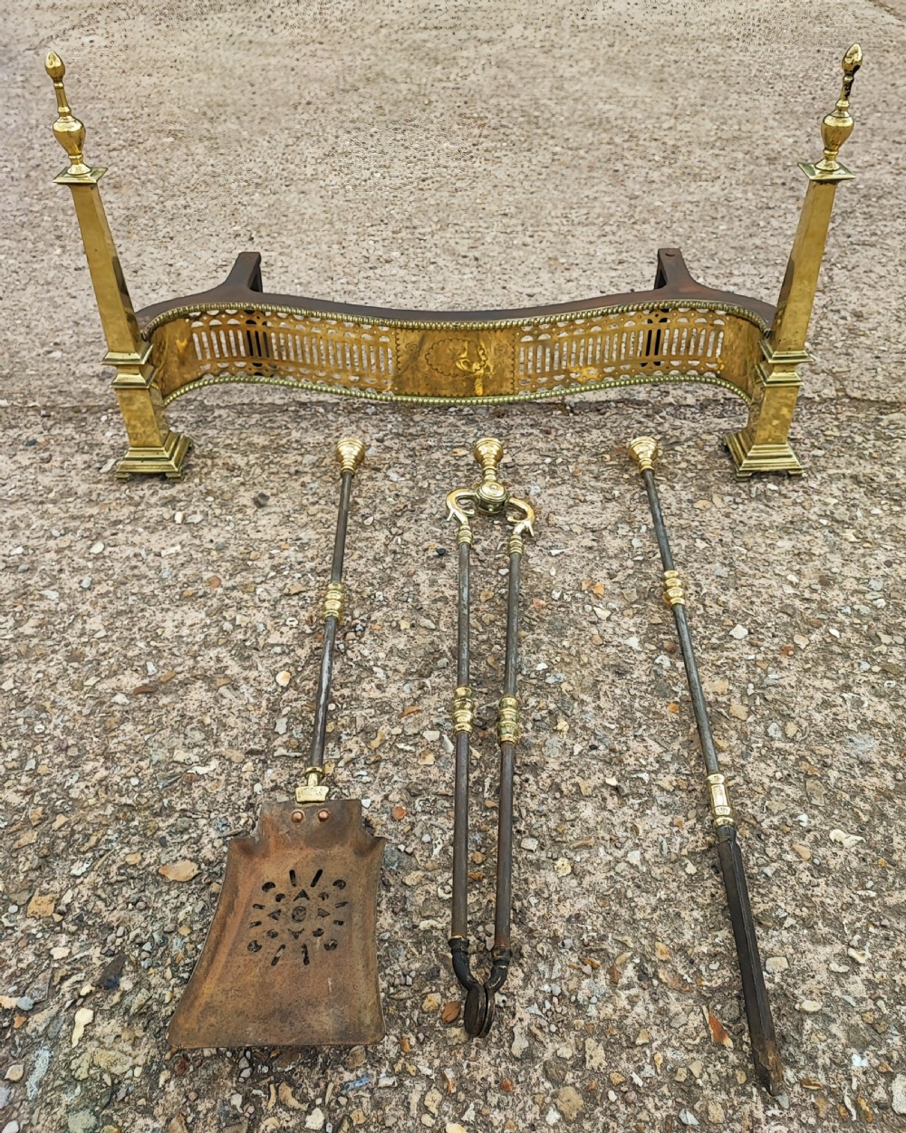 A superb antique serpentine fender and a set of 3 brass and iron fire irons.