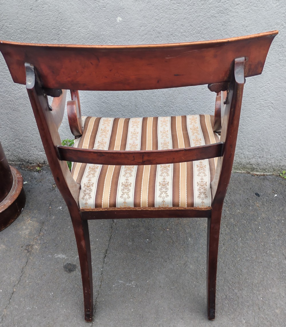 A Regency mahogany armchair with sweeping scroll armrests, a curved crest rail, turned front legs, and a striped upholstered seat. View X