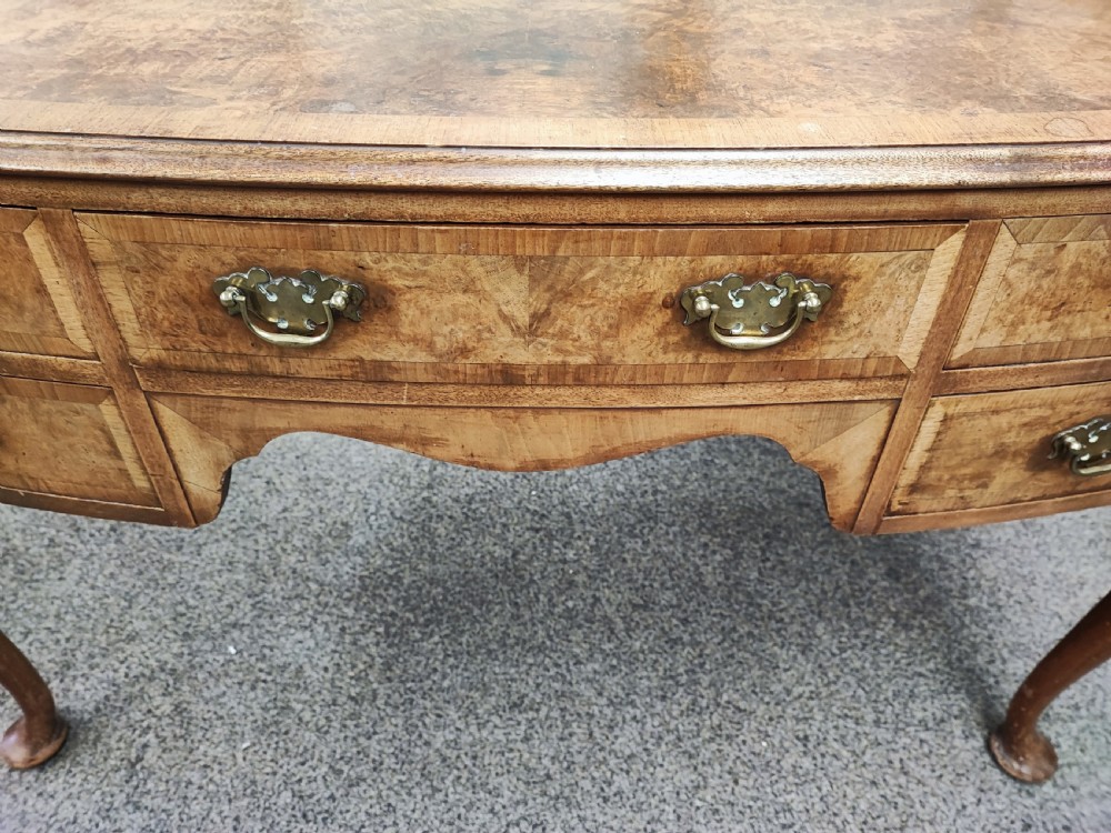 An antique golden burr walnut dressing table with five drawers, brass drop handles, and cabriole legs. View VI