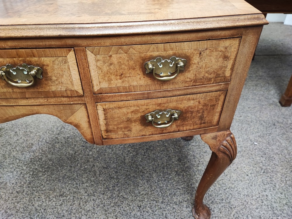 An antique golden burr walnut dressing table with five drawers, brass drop handles, and cabriole legs. View X