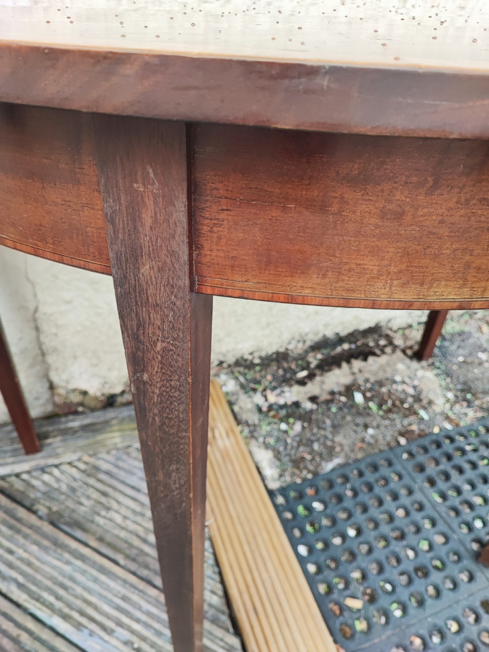 An oval Georgian style mahogany extendable dining table featuring a polished surface with crossbanded border detailing and four tapered square legs. View II