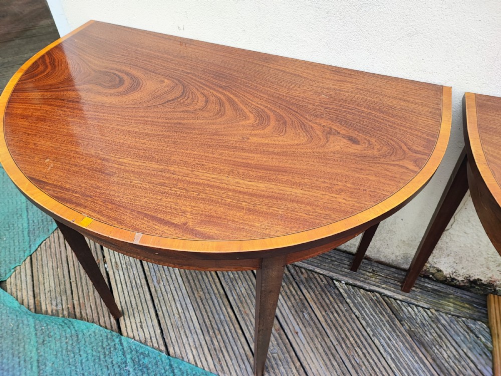 An oval Georgian style mahogany extendable dining table featuring a polished surface with crossbanded border detailing and four tapered square legs. View VI