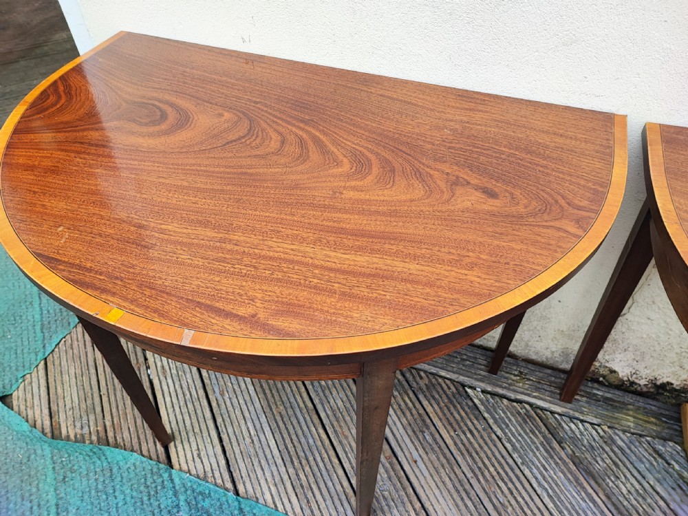 An oval Georgian style mahogany extendable dining table featuring a polished surface with crossbanded border detailing and four tapered square legs. View VII