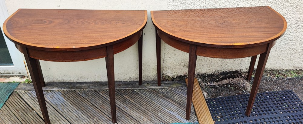 An oval Georgian style mahogany extendable dining table featuring a polished surface with crossbanded border detailing and four tapered square legs. View XI