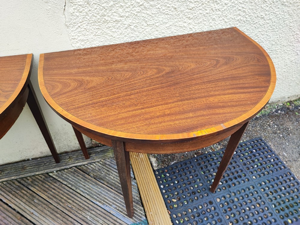 An oval Georgian style mahogany extendable dining table featuring a polished surface with crossbanded border detailing and four tapered square legs. View XII