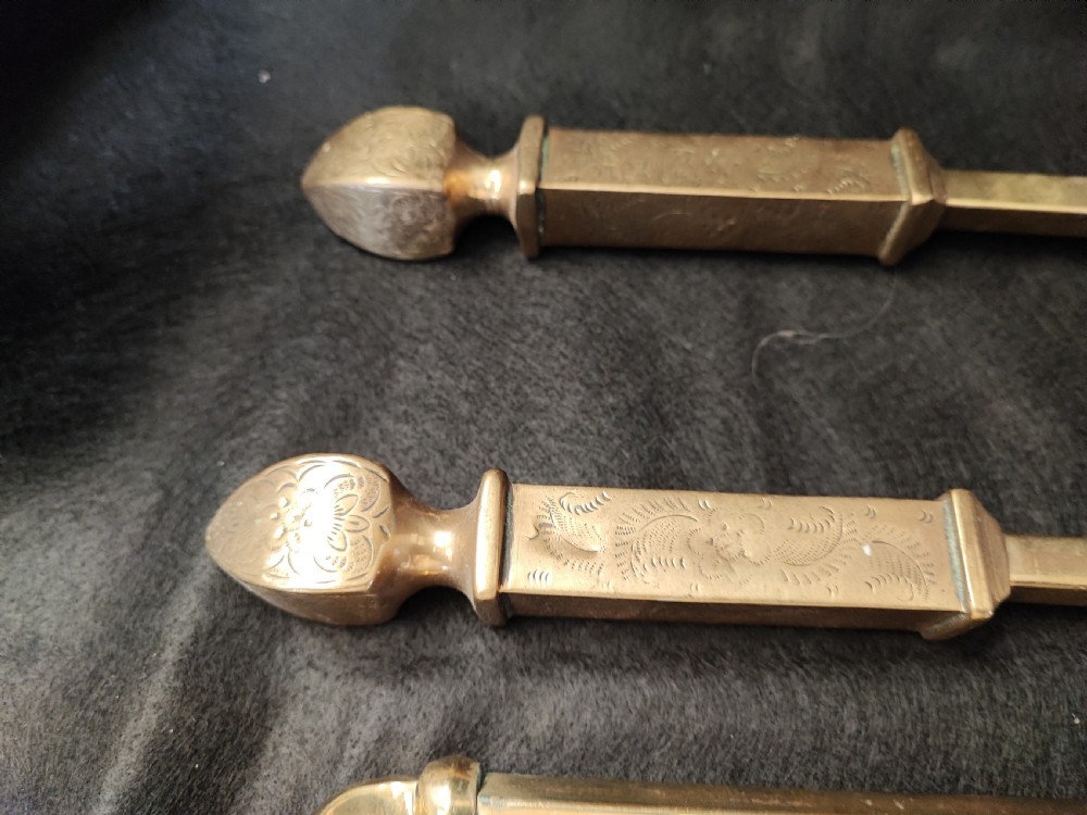 A set of three antique solid brass fire irons comprising a poker, tongs, and a shovel with a decorative shell pan. View III