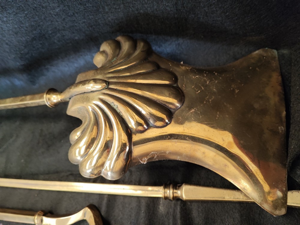 A set of three antique solid brass fire irons comprising a poker, tongs, and a shovel with a decorative shell pan. View V