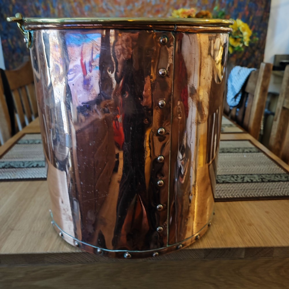 A cylindrical polished copper bucket featuring a riveted vertical seam, a rolled brass rim, and a band of rivets around the base. View VII