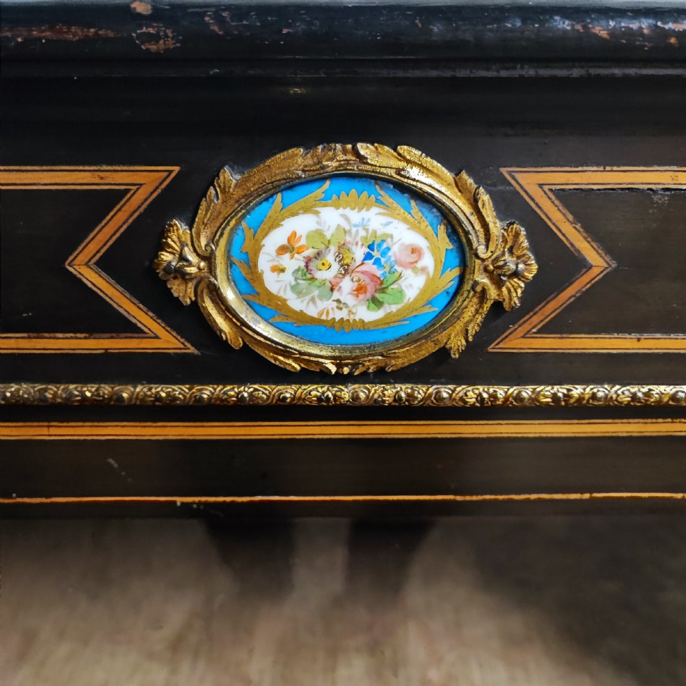 A black ebonised Victorian display cabinet featuring a central glazed door, gilt metal mounts, stringing inlay, and three porcelain plaques. View IV
