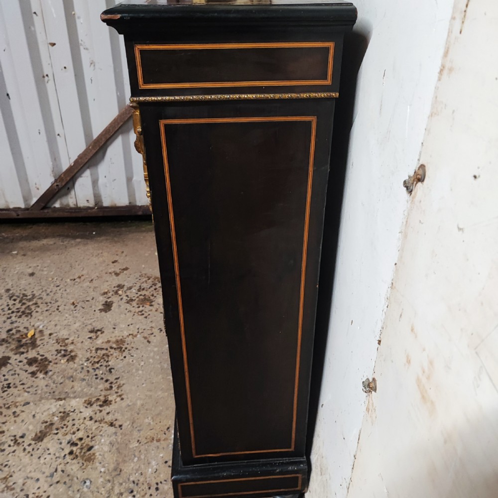 A black ebonised Victorian display cabinet featuring a central glazed door, gilt metal mounts, stringing inlay, and three porcelain plaques. View VIII
