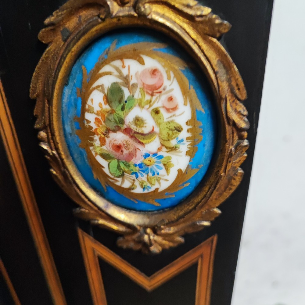 A black ebonised Victorian display cabinet featuring a central glazed door, gilt metal mounts, stringing inlay, and three porcelain plaques. View IX