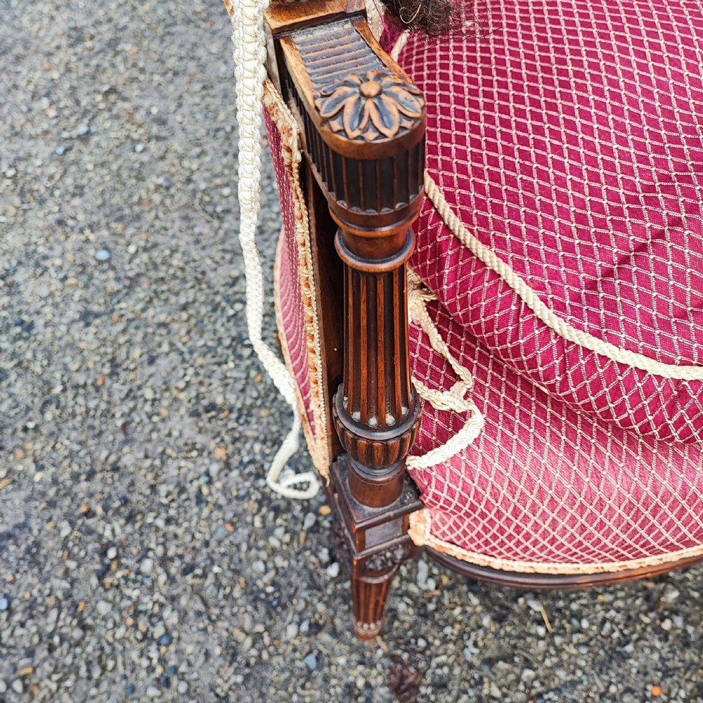 An antique French Louis XVI style wingback armchair crafted from mahogany with patterned red textile upholstery and fluted legs. View VIII