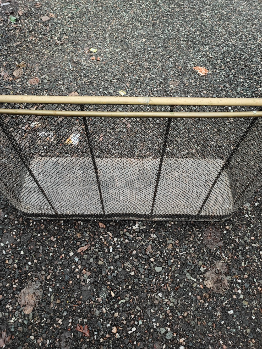 An antique nursery fireguard with a black woven wire mesh body, curved sides, and an upper tubular brass rail. View VII