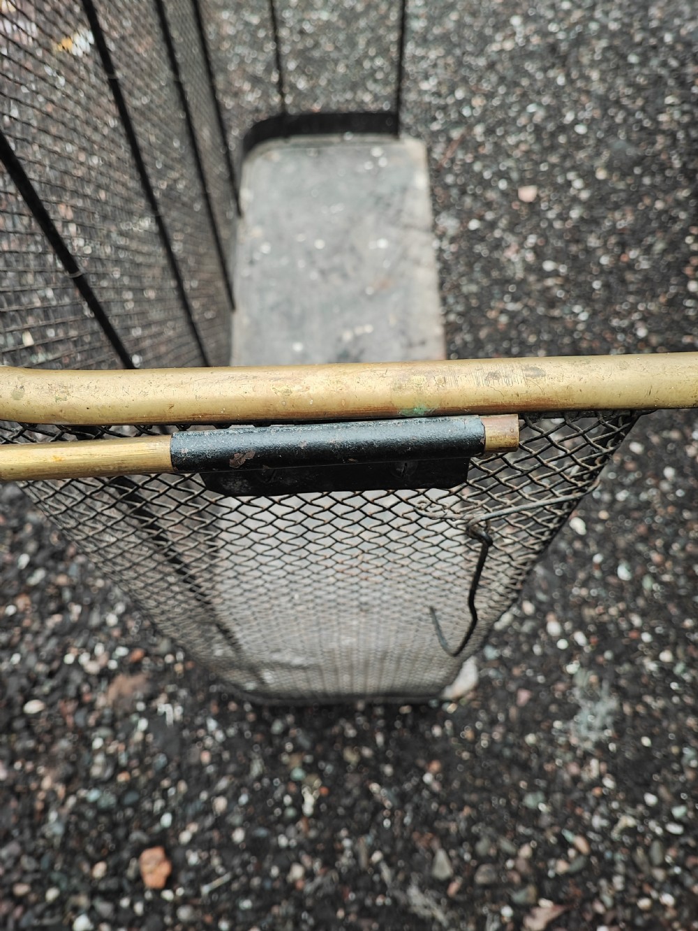 An antique nursery fireguard with a black woven wire mesh body, curved sides, and an upper tubular brass rail. View VIII