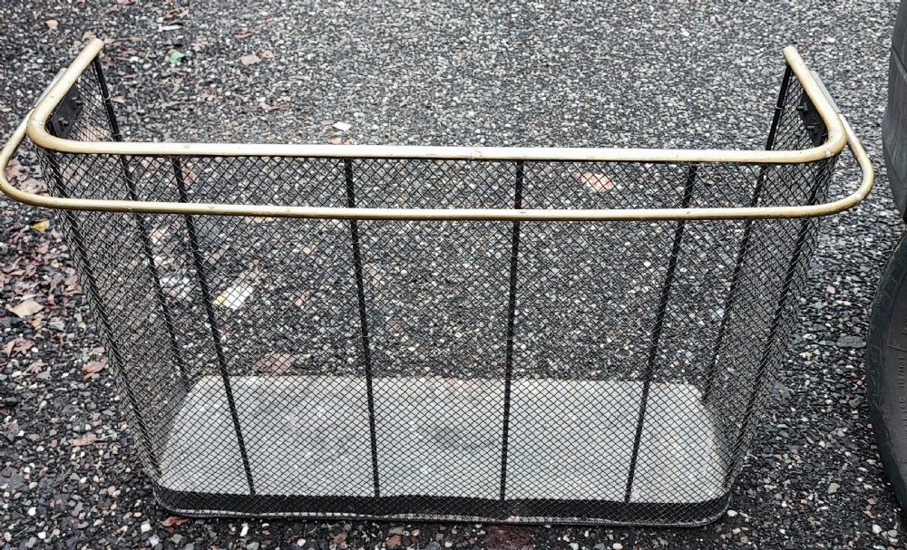 An antique nursery fireguard with a black woven wire mesh body, curved sides, and an upper tubular brass rail. View XI