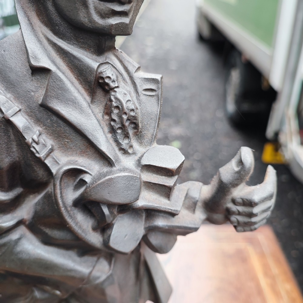 A dark cast metal companion set stand depicting a golfer caddy holding a flag pole and carrying a golf bag on a rectangular base. View III