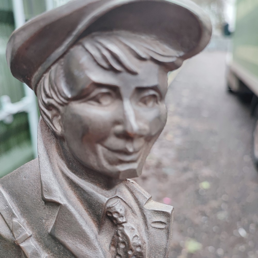 A dark cast metal companion set stand depicting a golfer caddy holding a flag pole and carrying a golf bag on a rectangular base. View IV