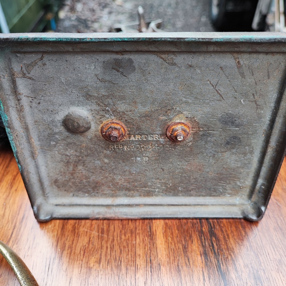 A dark cast metal companion set stand depicting a golfer caddy holding a flag pole and carrying a golf bag on a rectangular base. View VII