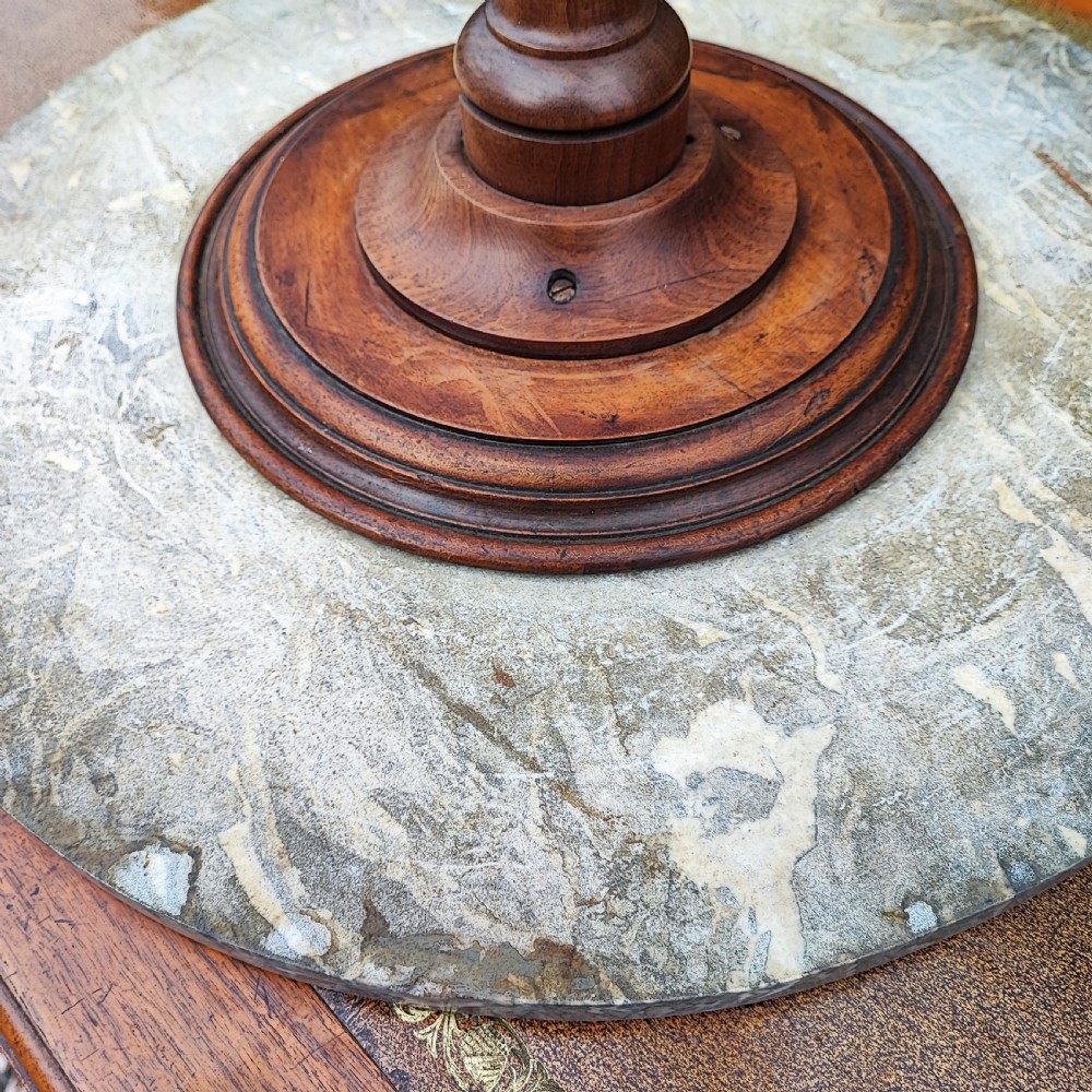 A circular grey variegated marble top side table featuring a turned wooden pedestal column and a tri-form base. View II