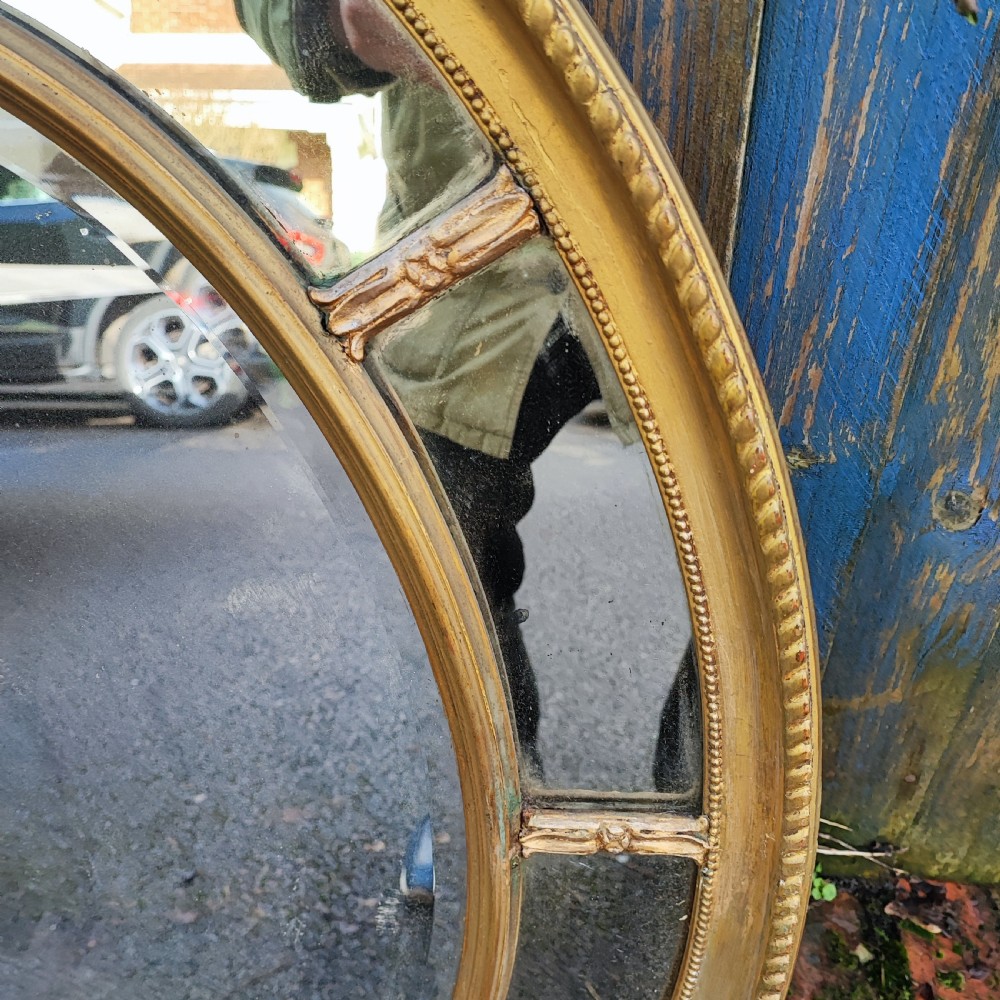 A large gold gilt oval wall mirror featuring a rope twist outer moulding and segmented glass border surrounding an inner oval mirror pane. View III