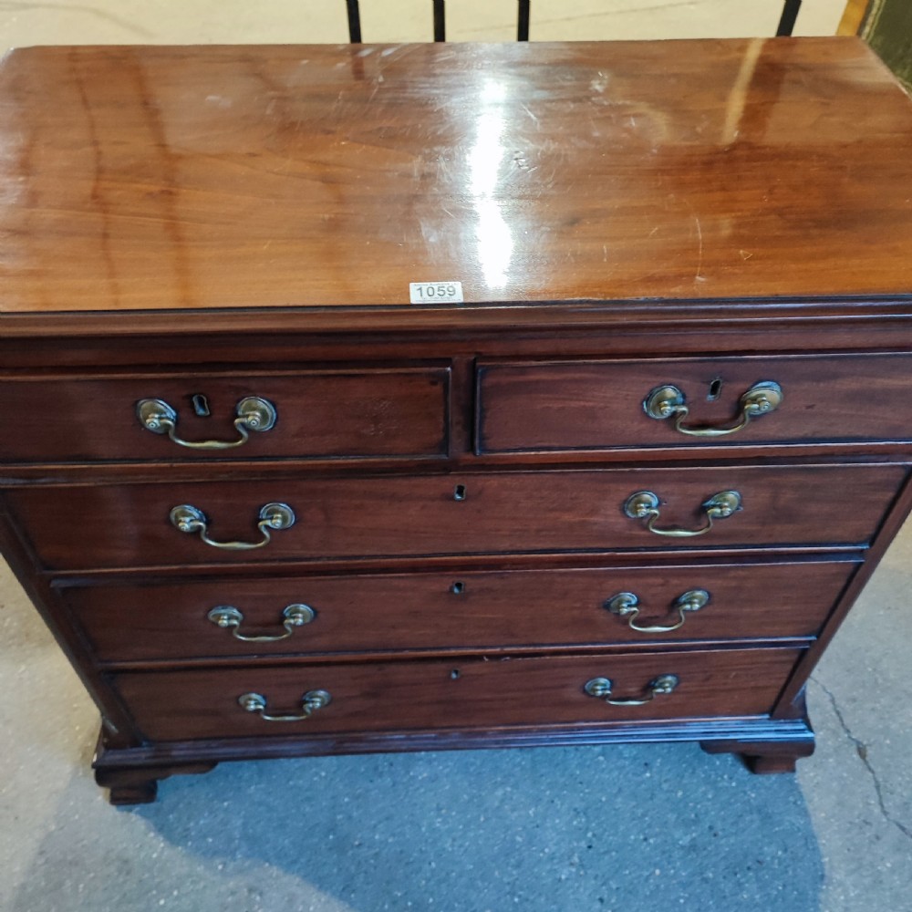A Georgian mahogany chest of drawers with two short drawers over three long graduated drawers, finished with brass swan-neck handles and bracket feet. View II