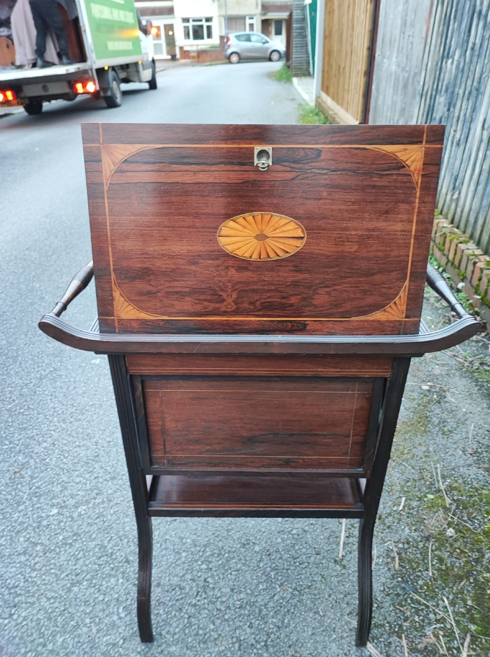 An antique rosewood work table featuring top marquetry inlay with a central sunburst motif, turned side handles, a lower shelf, and curved legs. View V