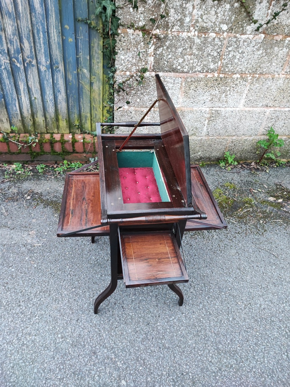 An antique rosewood work table featuring top marquetry inlay with a central sunburst motif, turned side handles, a lower shelf, and curved legs. View VI