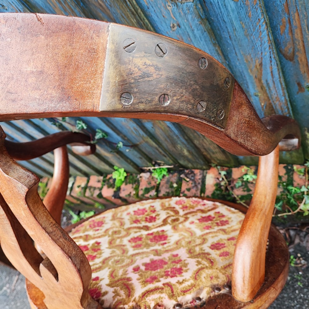 A Victorian mahogany revolving desk chair featuring a curved horseshoe armrest, a pierced central back splat, and an upholstered circular seat. View V