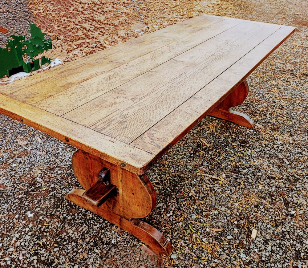 A long antique oak refectory table featuring a wide plank top with cleated ends and a trestle base secured with wooden keys.
