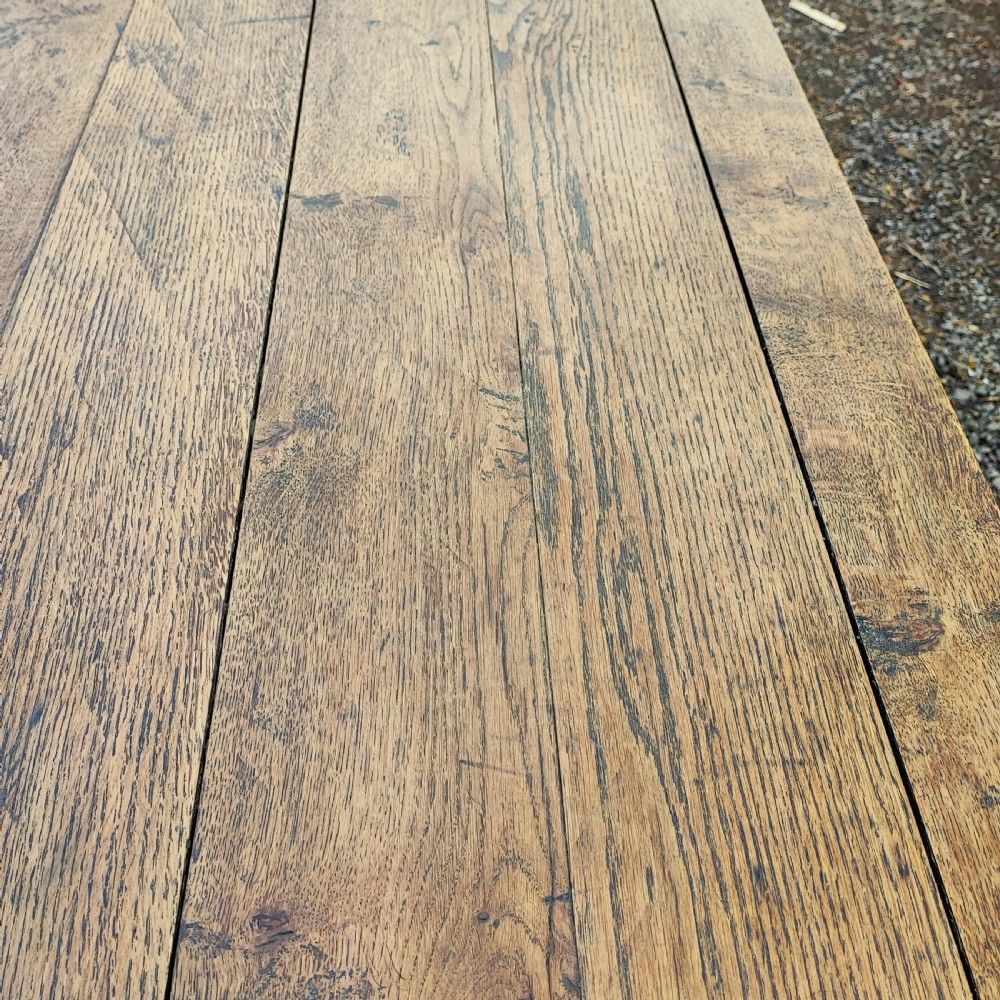 A long antique oak refectory table featuring a wide plank top with cleated ends and a trestle base secured with wooden keys. View IV