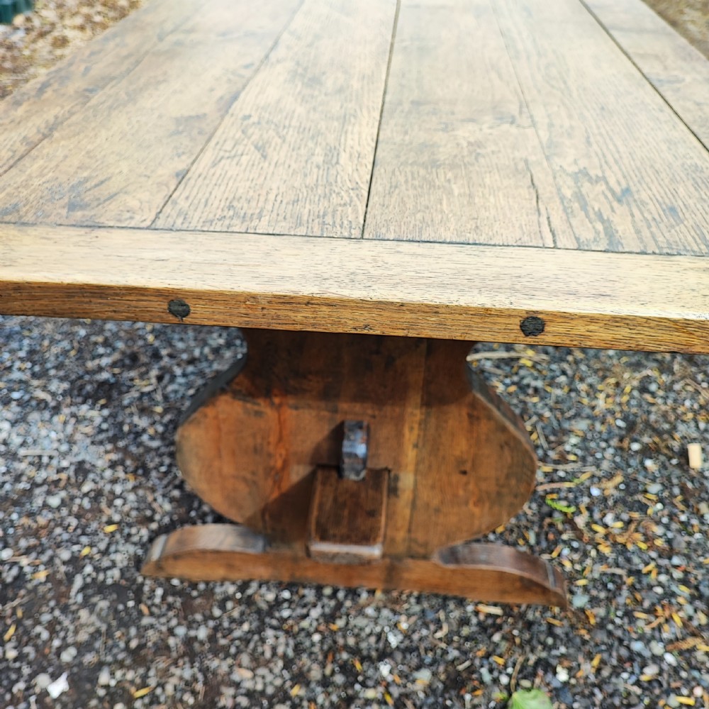 A long antique oak refectory table featuring a wide plank top with cleated ends and a trestle base secured with wooden keys. View V