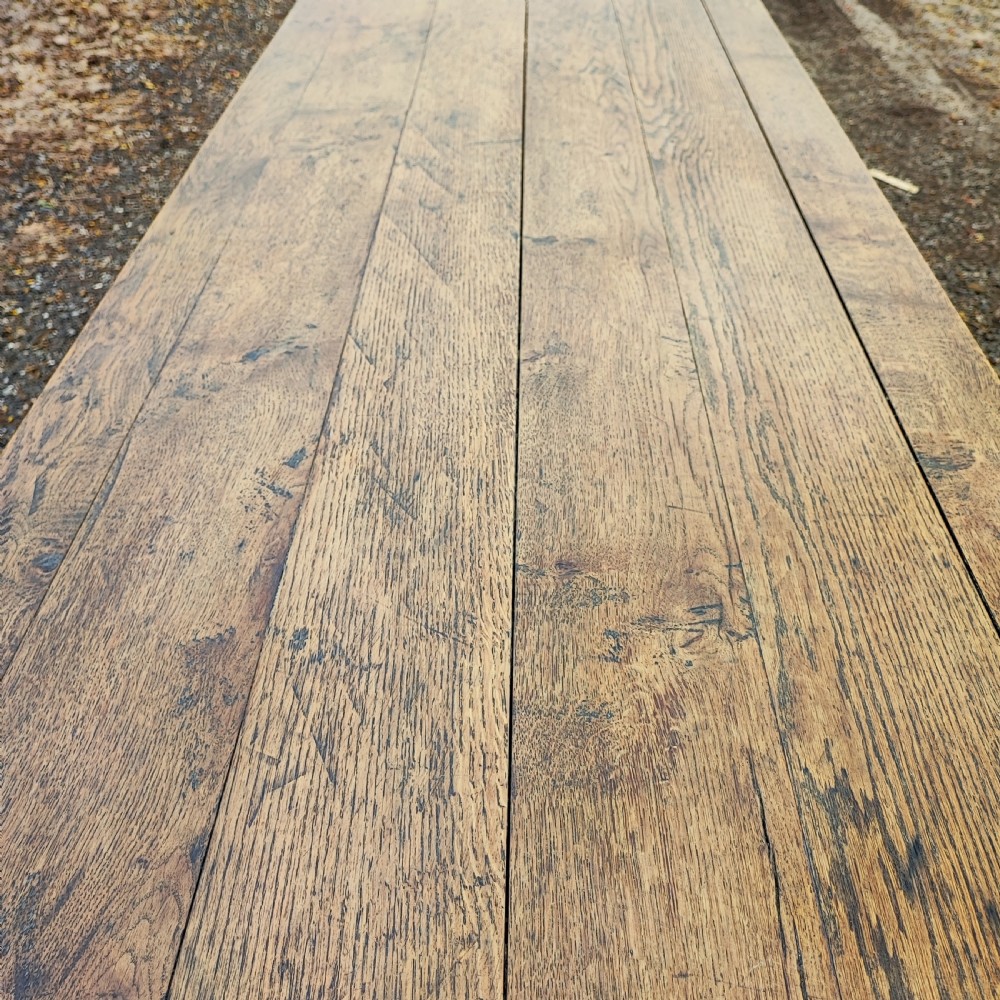 A long antique oak refectory table featuring a wide plank top with cleated ends and a trestle base secured with wooden keys. View VI